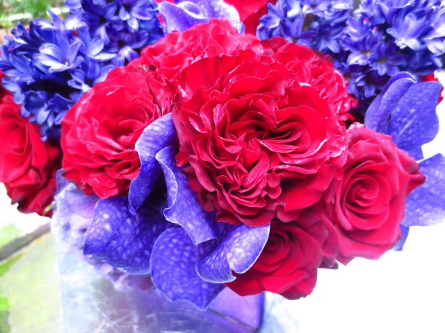 another close up of flower arrangement with roses, hydrangeas and orchids on a patio table this time focusing on the roses