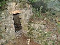 Detall de la porta amb la llinda plana i el mur de reforç de la barraca de vinya de la Vinya Vella de Rubió