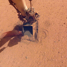 An animated GIF showing the InSight Mars lander's robotic arm pressing down on the self-digging 'mole' (not visible) as it burrows into the Martian soil...on January 9, 2021.