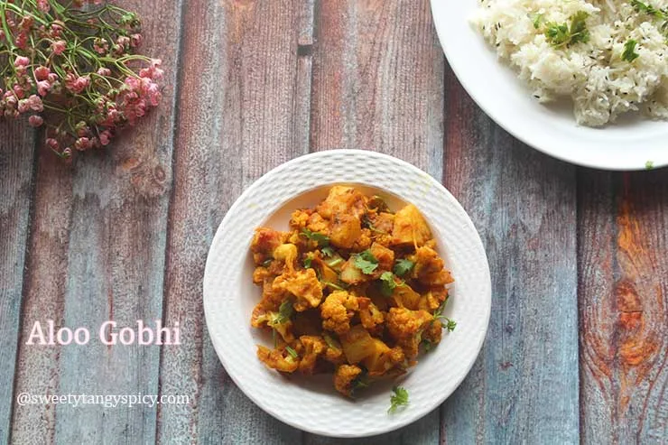 "A mouthwatering platter featuring Aloo Gobhi, a classic North Indian dish with potatoes and cauliflower, served alongside aromatic Jeera Rice, a flavorful and cumin-infused basmati rice, creating an irresistible Indian feast for your senses."