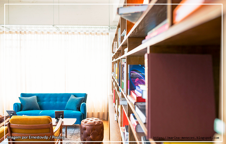 A foto mostra uma sala de estar com um sofá turquesa. Ao lado do sofá, várias estantes de livros dispostas