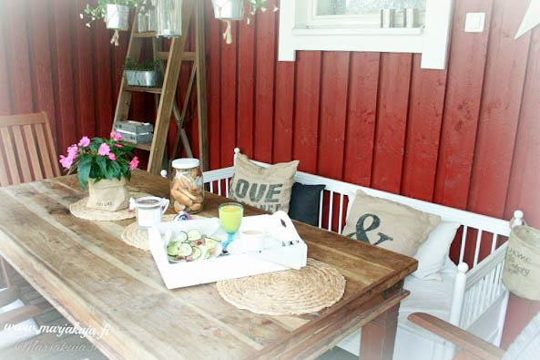 ruskea pöytä  ja valkoinen puusohva terassilla.