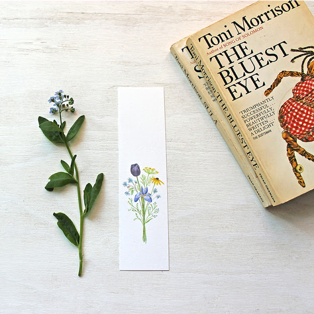 A paper bookmark with a bouquet in watercolor and a worn copy of The Bluest Eye by Toni Morrison