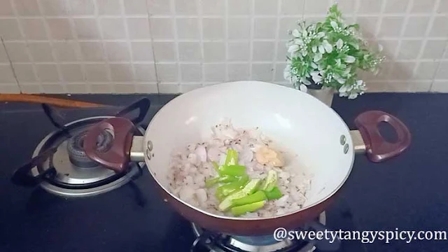 The ginger-garlic paste and chopped green chilies are stirred into the sautéed onions in the pan, releasing a delightful aroma as they cook until the raw smell dissipates.