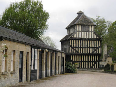 A one-storey stone coach house or garage and three storey half-timbered building