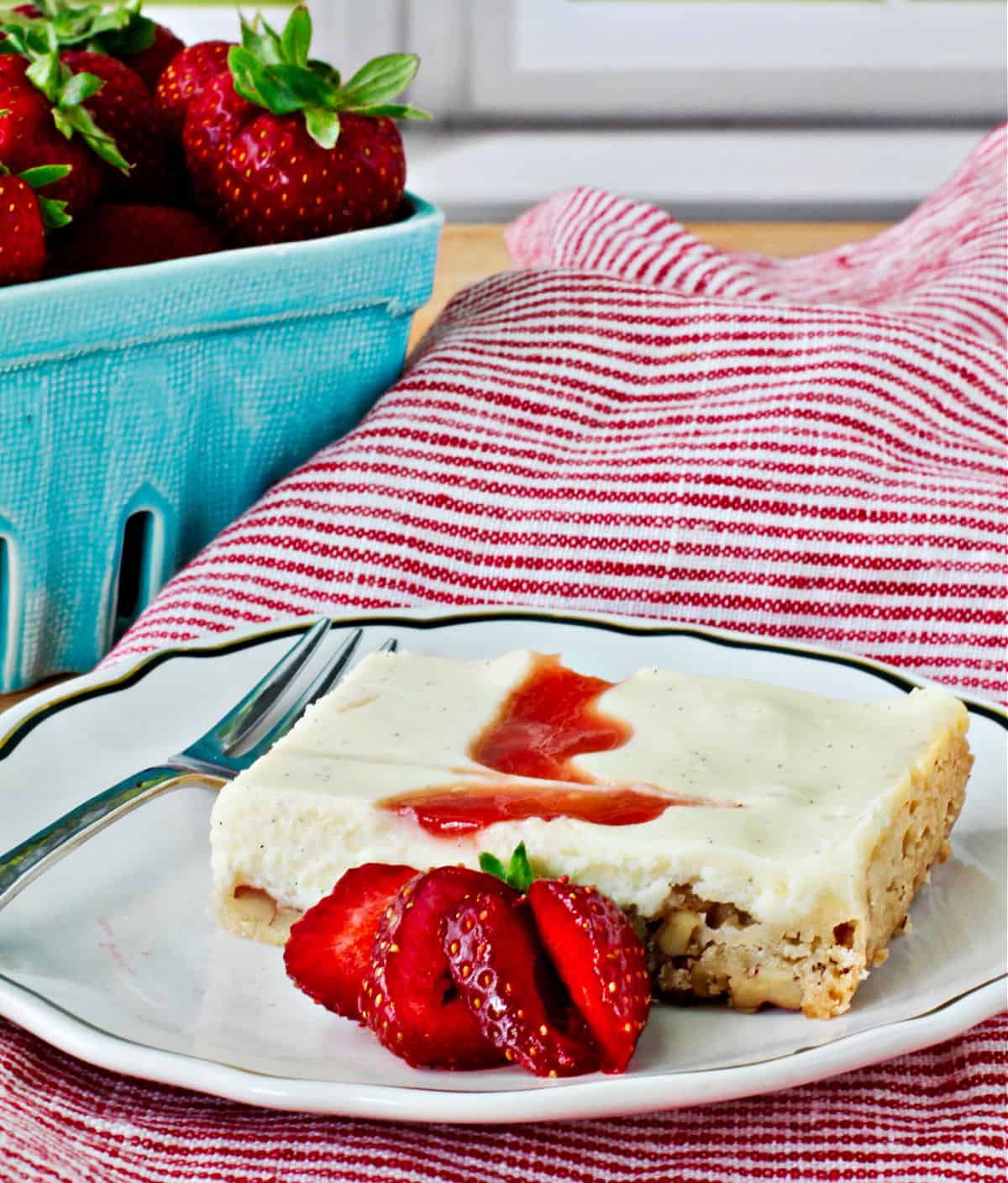 Strawberry Cheesecake Bar on a plate with strawberries in a basket.