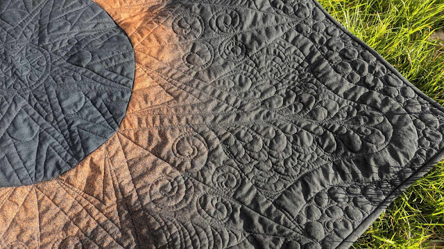 Solar eclipse quilt made by bleaching black fabric