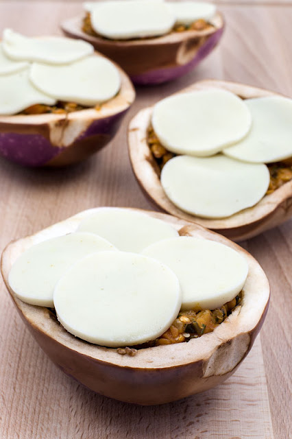 Stuffed eggplants with red lentils and vegan mozzarella bafore baking on a board