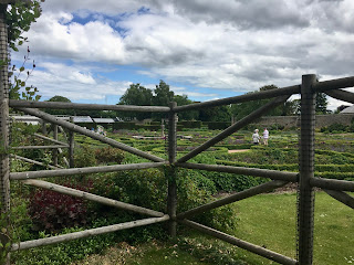 A wooden fence with maze-like landscape features behind it.