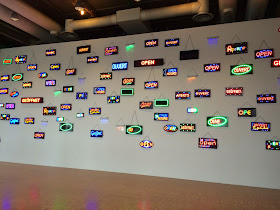Pic of neon-lit "open" signs in multiple languages at modern art gallery entrance