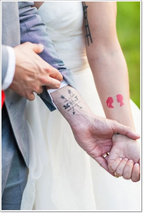 una pareja en el dia de su boda, enseñan sus tatuajes de pareja