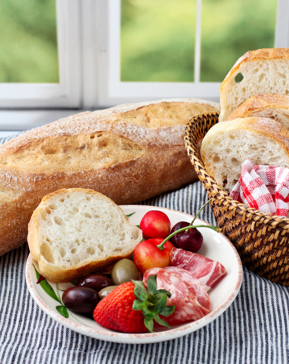 French bread with fruit and charcuterie on a plate.