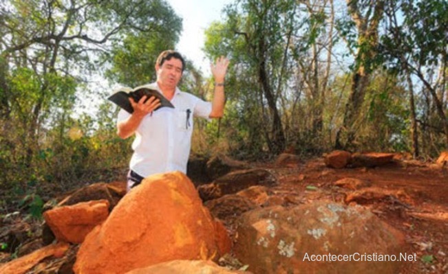 Pastor orando con Biblia en un monte