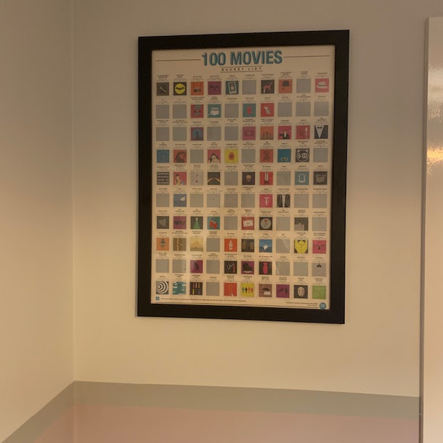 100 Movies scratch-off poster, framed on wall