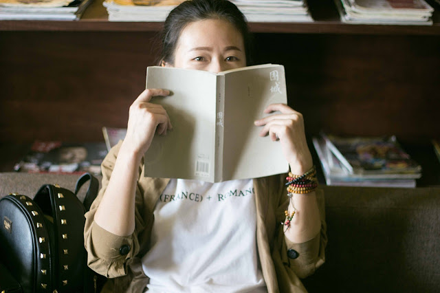 Mother covering half of her face with a book, looking at you, example