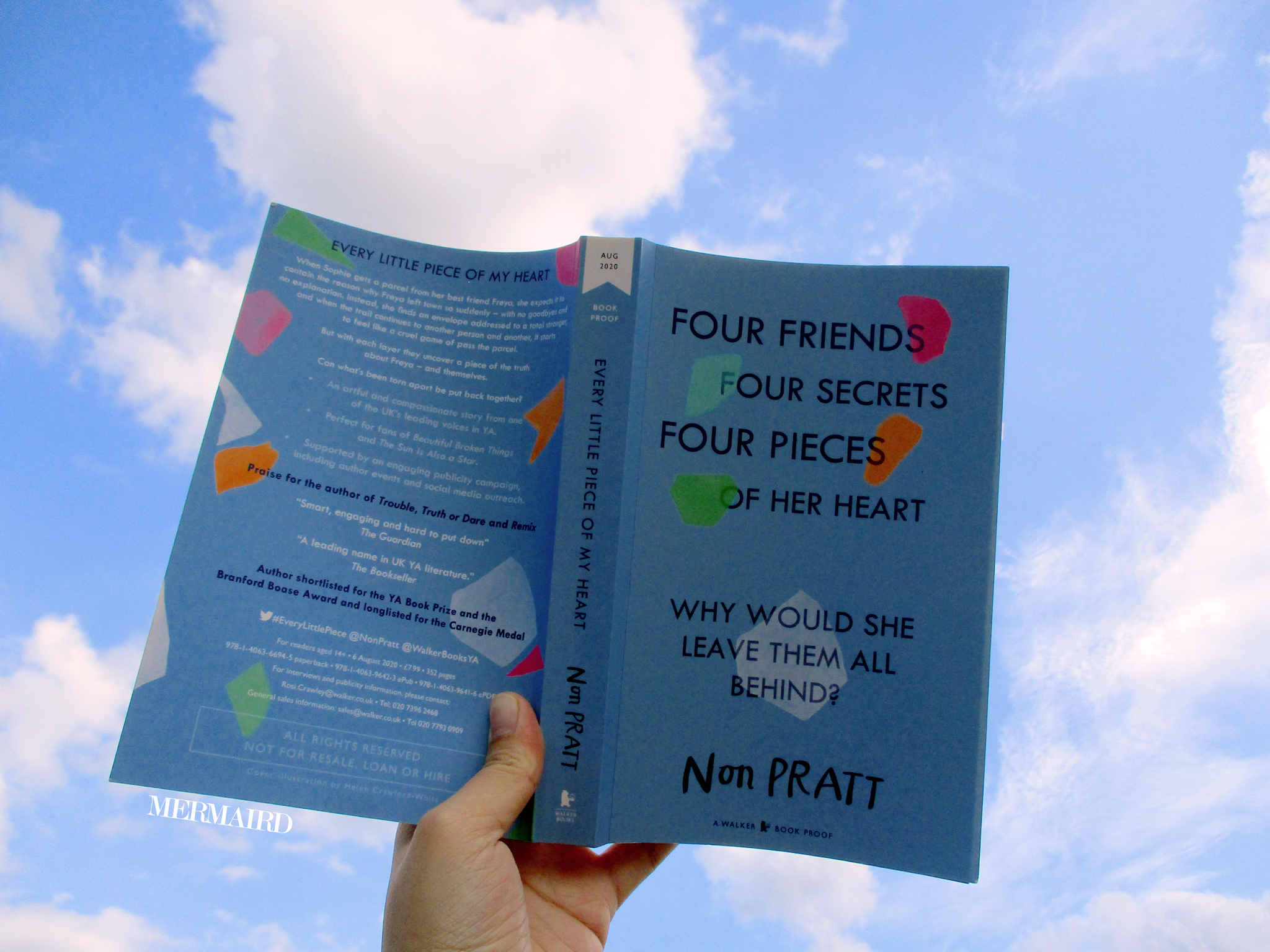 A book with blue cover being held open against bright blue sky