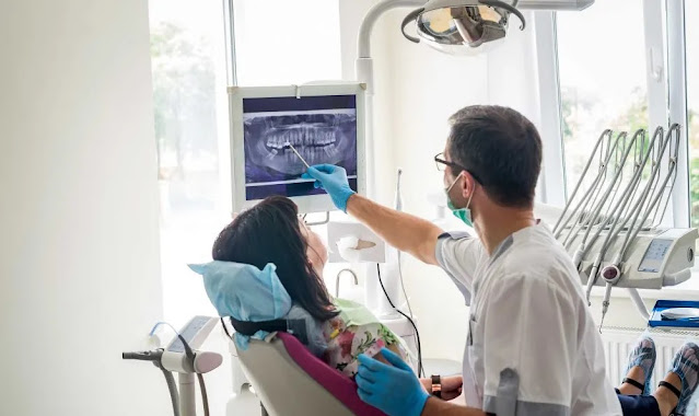 un dentista che mostra la panoramica dentale a una donna di 40 anni