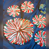 Mixed red, white, and green coaster and trivet with flower petal edges knit in garter stitch