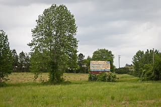 trees, green grass, and an old hotel sign on a humid NC day