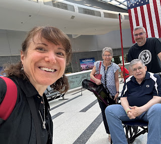 A selfie of me (in the foreground) and my parents and brother, with an American flag in the background.