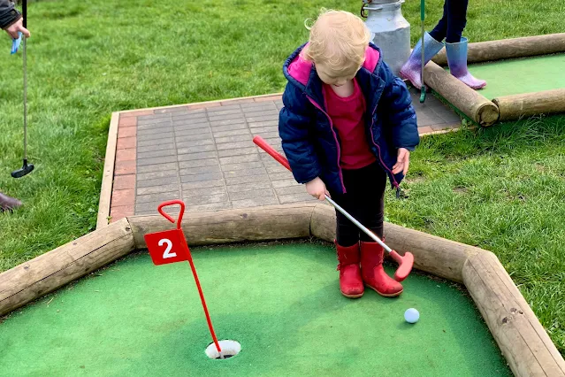 A preschooler playing mini golf and holding the club incorrectly