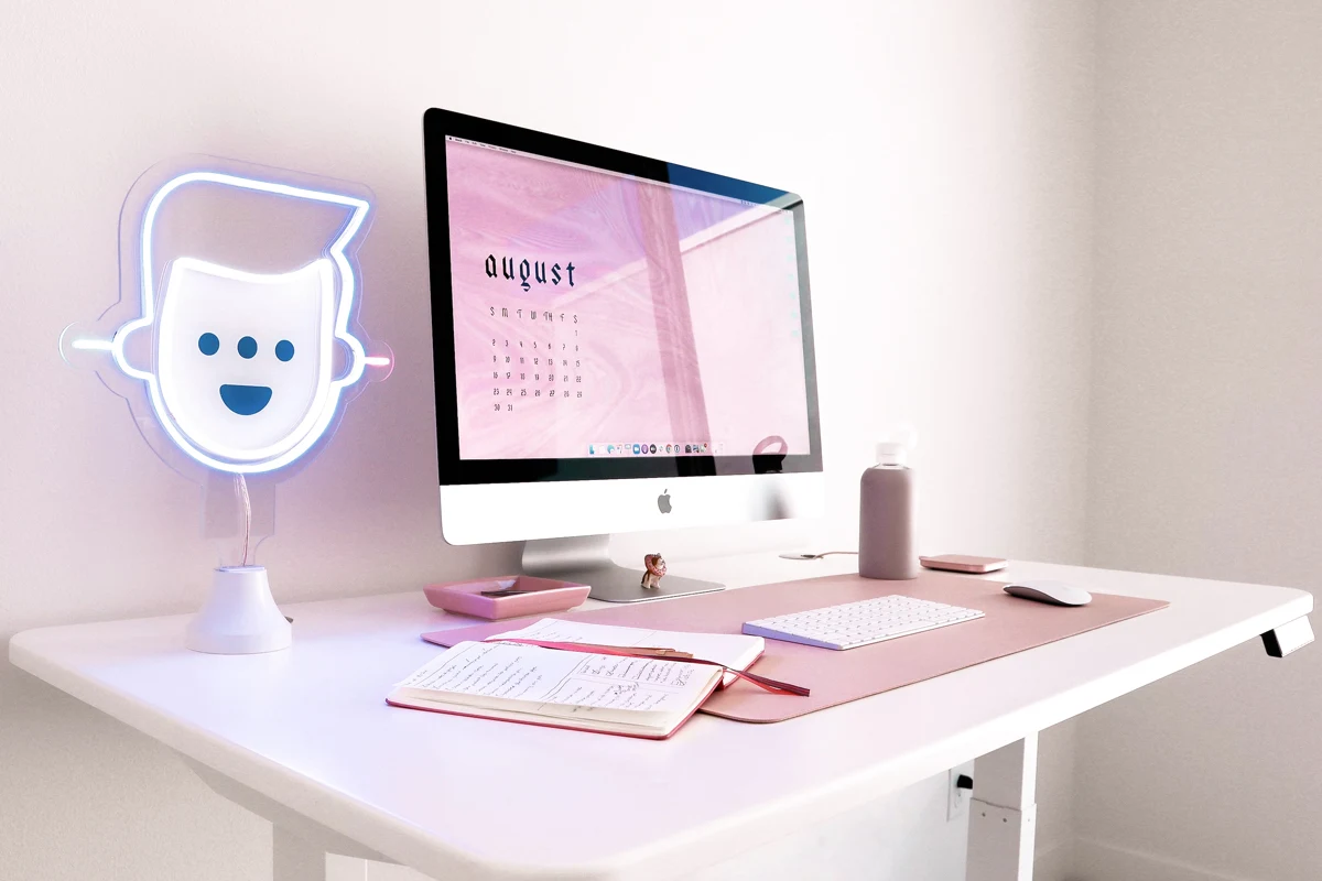 a very cute home office set-up with a personalized neon sign on a table, a big flat screen and a computer mouse