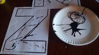 Drag string through black paint then drag it across the letter Z to make stripes.