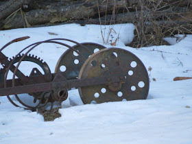 old rusted farm machinery and gears against the snow