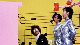 two silver clad japanese singers being hit with hammers