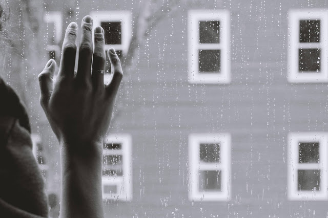 hand on window with raindrops sad:Photo by Kristina Tripkovic on Unsplash