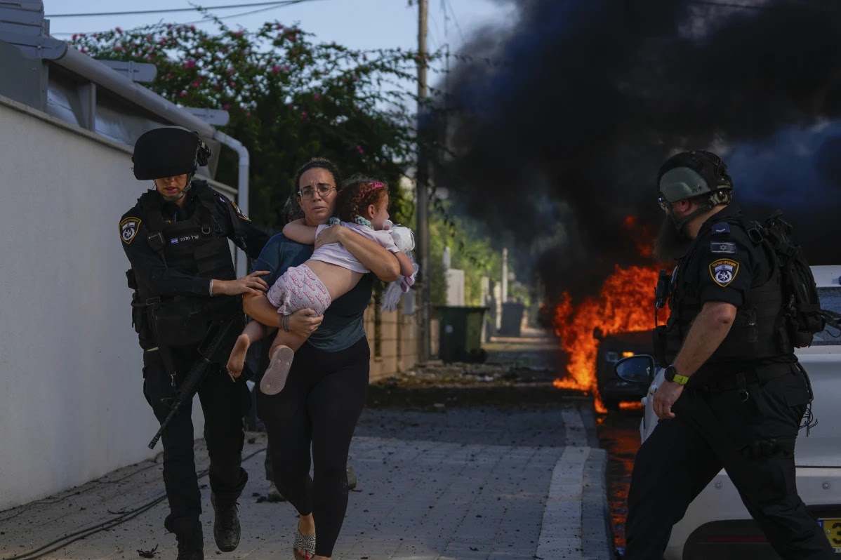 Police officer helps woman and child evacuate as fighting between Hamas and Israel intensifies