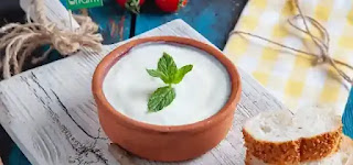 A bowl of yogurt next to pieces of bread