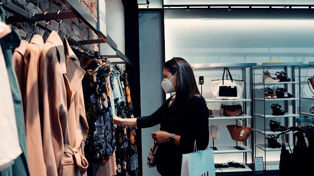 woman wearing a face mask browsing through clothes on display