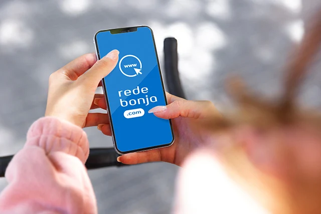 Mão feminina segurando um smartphone. Na tela, o site Rede Bonja (redebonja.com)