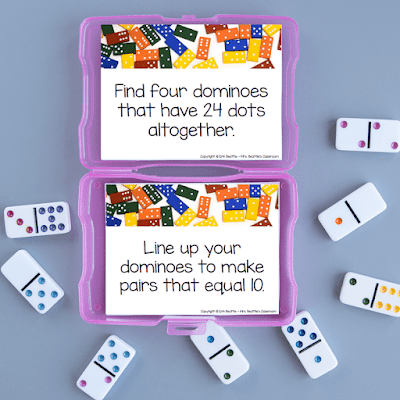 Photo of task cards in purple container with dominoes next to it.