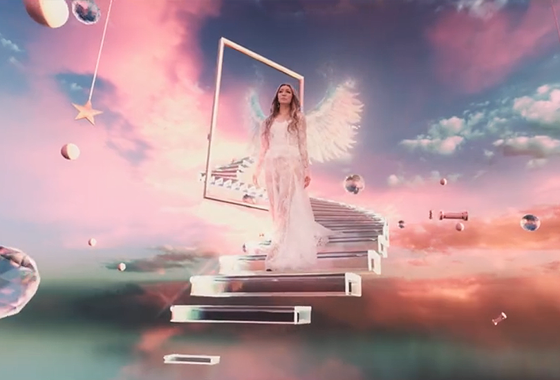 A shot from the music video of “Wings”, featuring Kumi Koda in a white lace dress and large white angel wings, as she walks down a glass set of steps, in a sunset drenched backdrop, within a location which looks like a different dimension or a form of limbo.