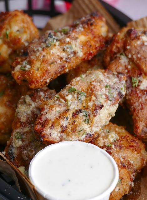 wings in a basket with a cup of ranch on the side.