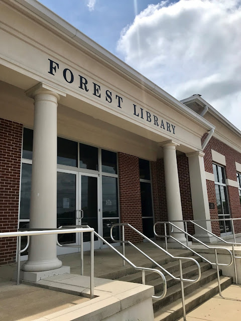 The outside of Forest Library, with large columns, metal handrails, and large glass doors