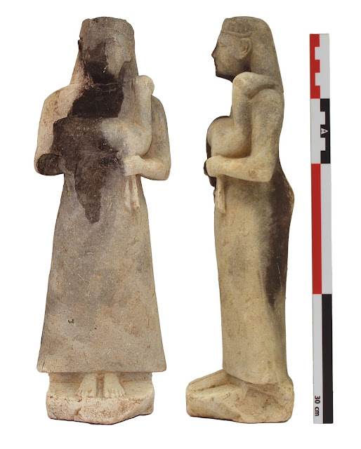 Λίθινο αγαλματίδιο, ύψους 31εκ., που αναπαριστά γυναικεία μορφή με διάδημα και μακρύ ένδυμα που κρατά στην αγκαλιά της ένα ζώο (ελάφι;) (αρχές 6ου αι. π.Χ.)