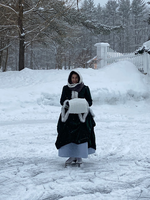 the author standing on the ice with snow behind her in the skating outfit