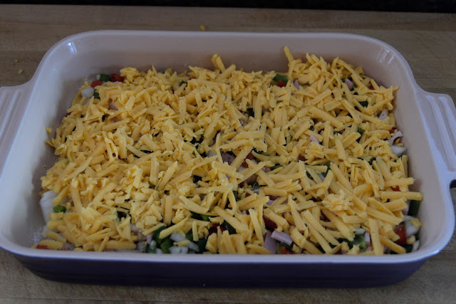 Cheese being added to the casserole dish. 