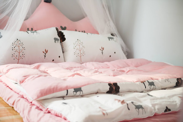 A girly bed spread in pink and white.