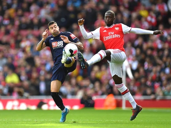 Nicolas Pepe of Arsenal is challenged by Diego Rico of AFC Bournemouth during the Premier League match between Arsenal FC and AFC Bournemouth at Emirates Stadium on October 06, 2019 in London, United Kingdom