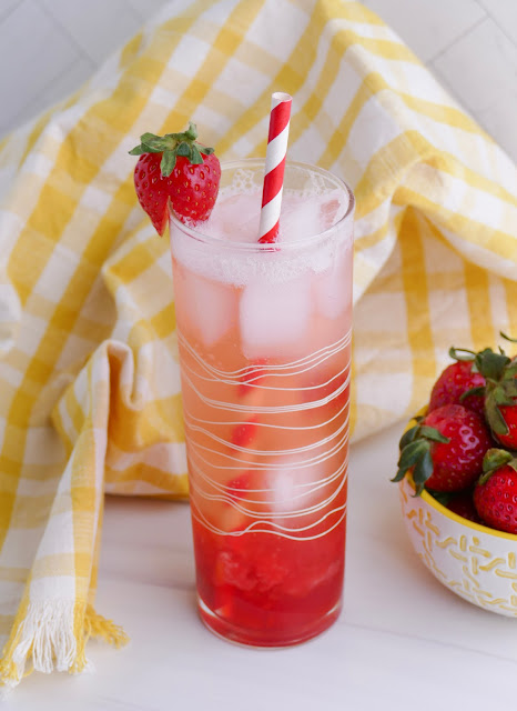 Homemade Fresh Strawberry Soda in a tall glass with a straw and strawberry garnish.
