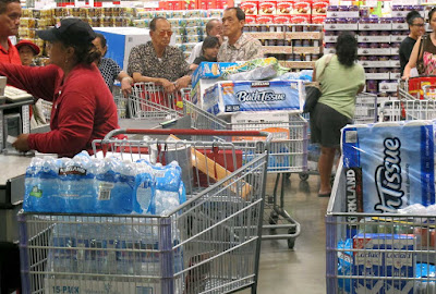 People in a store, buying toilet paper and water in bulk