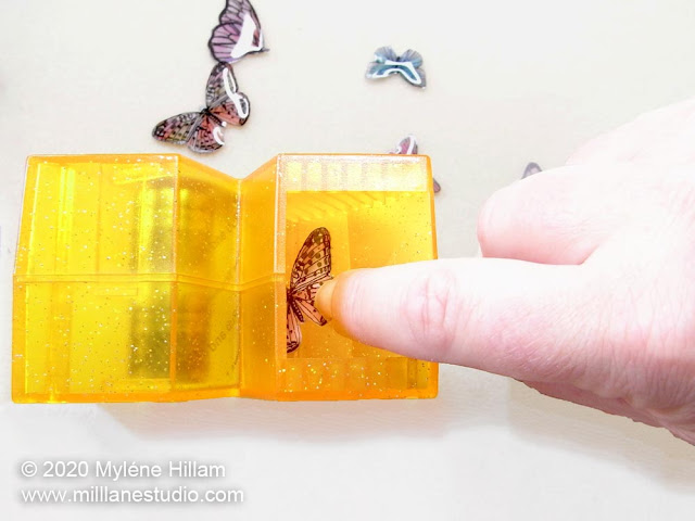 Placing the resin-coated butterfly into the well of the sticker making machine