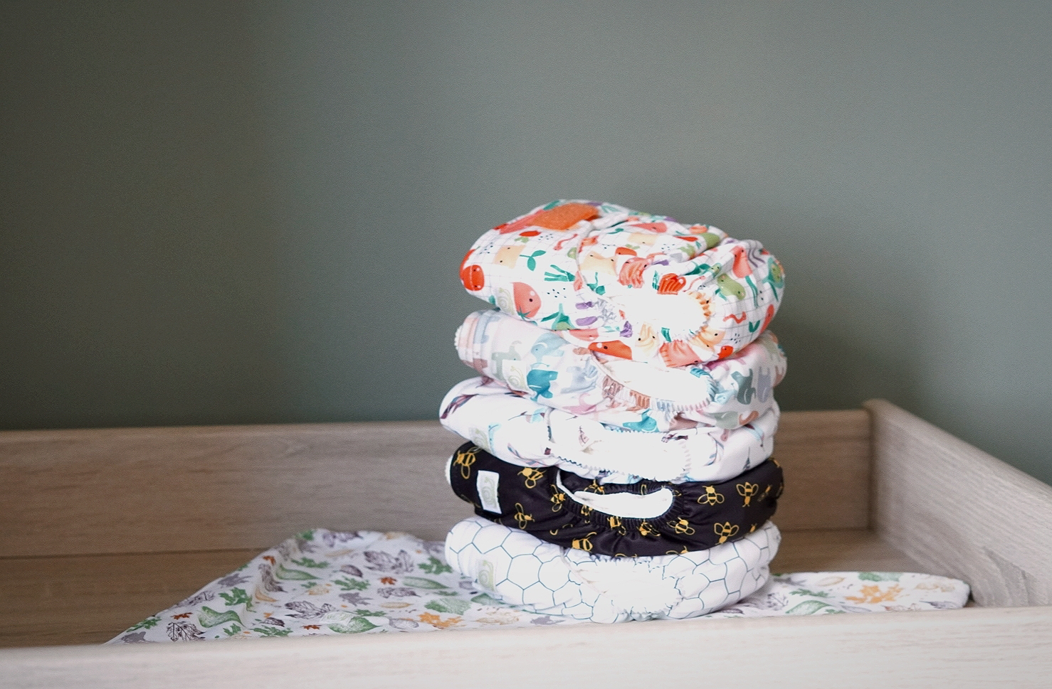 a stack of reusable nappies in various patterns on a changing table