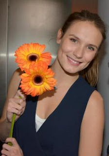 Ana Girardot tenant des fleurs et souriant