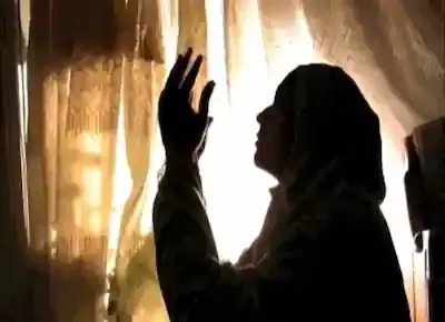 امرأة ساجدة ترفع يديها وتقوم بالدعاء إلى الله