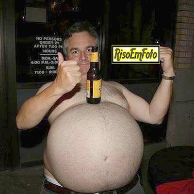 Homem gordo e barrigudo equilibra cerveja sobre o imenso abdome. 